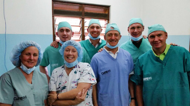 Group in OR scrubs smiles for camera.